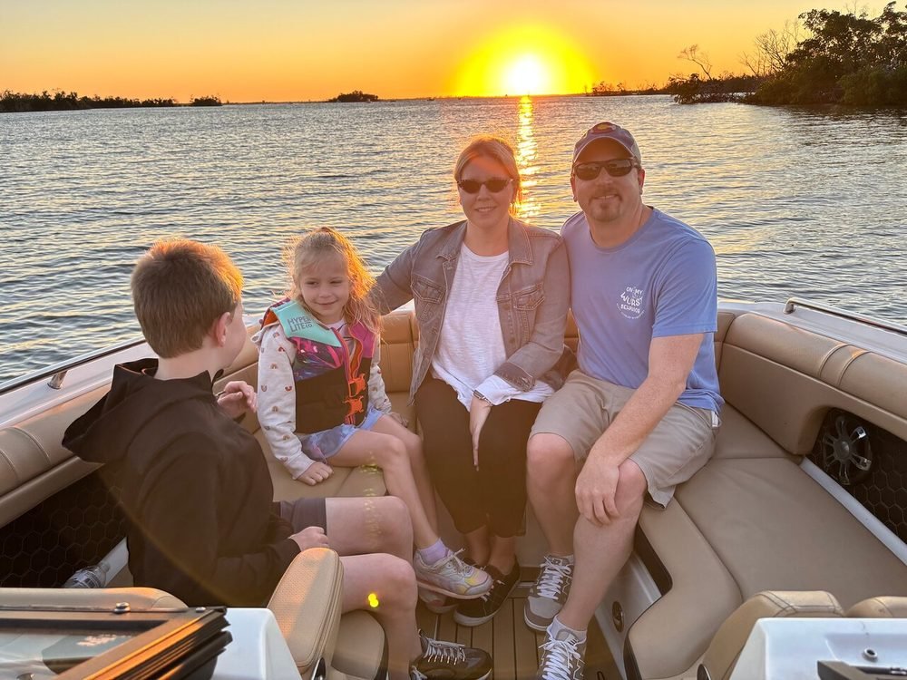 A family of four relaxing together on a private sunset boat cruise in Cape Coral at golden hour