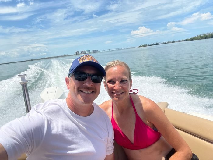 A couple enjoying the ride as the boat's wake fans out behind them, marina skyline in the background