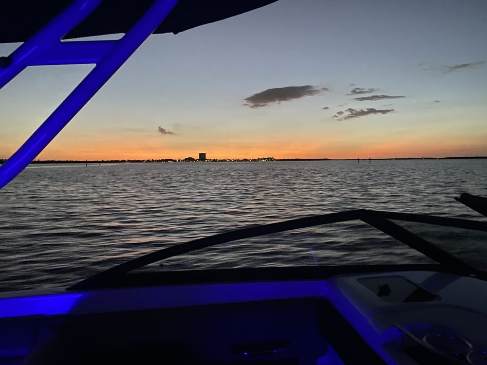 Two guests silhouetted at the bow of the boat watching the sunset