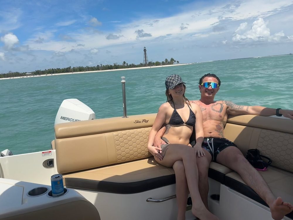 Guests aboard a private boat tour with the Sanibel Lighthouse and turquoise water in the background