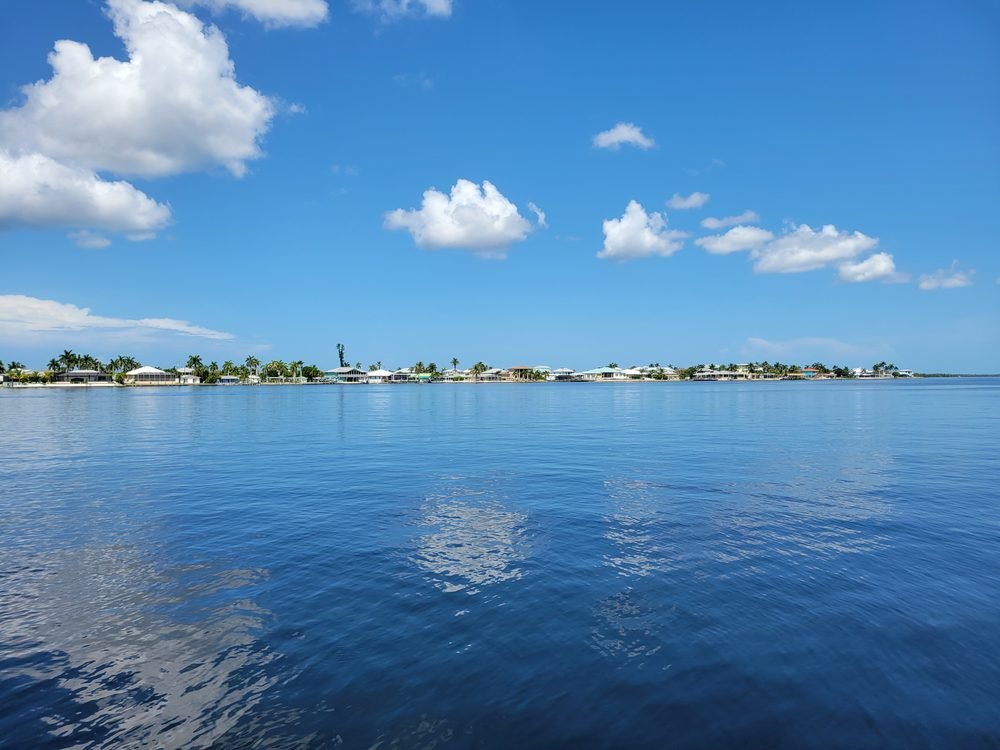 Calm open water with Southwest Florida waterfront homes and palm trees in the distance